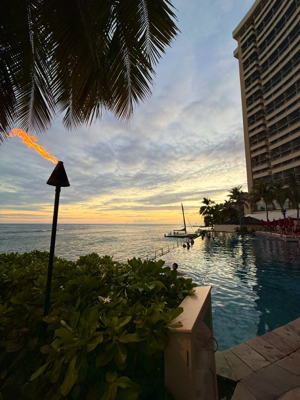 Fackel und Palme am Infinity Pool bei Sonnenuntergang